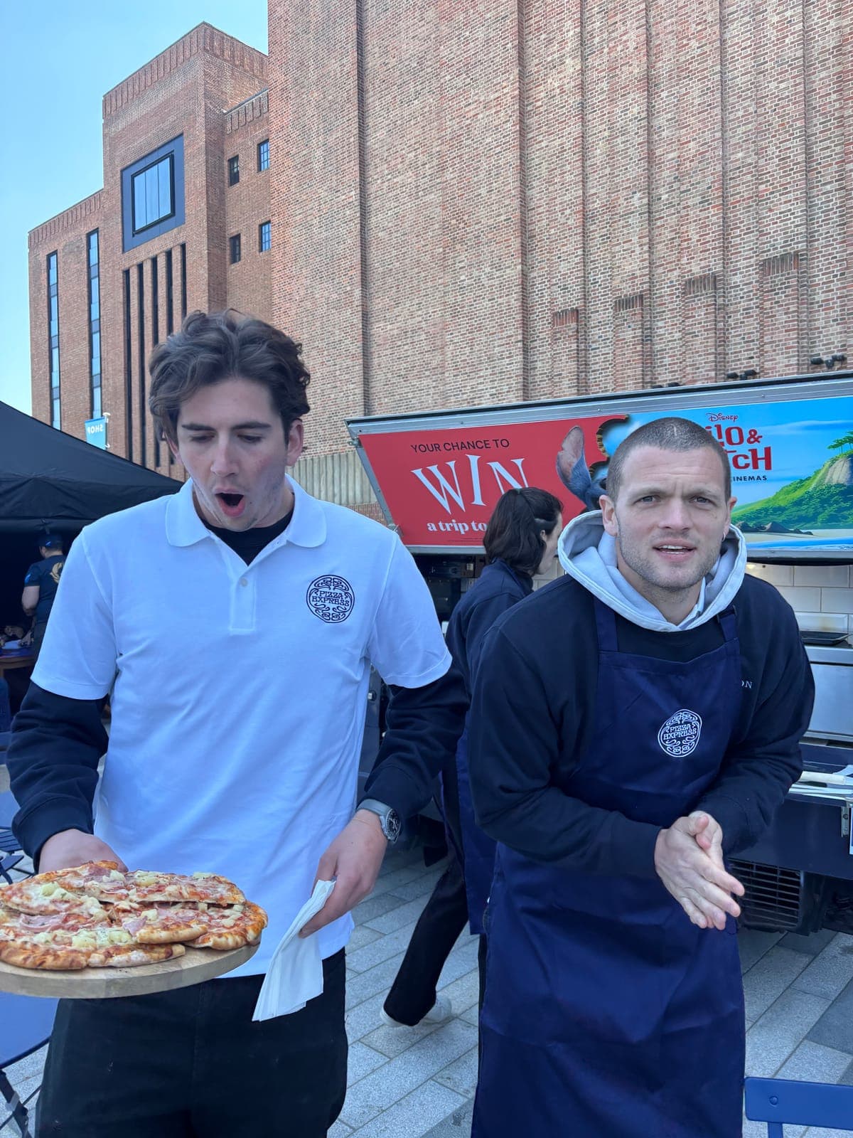 Louis carrying a tray of pizzas at a Battersea Power Station event