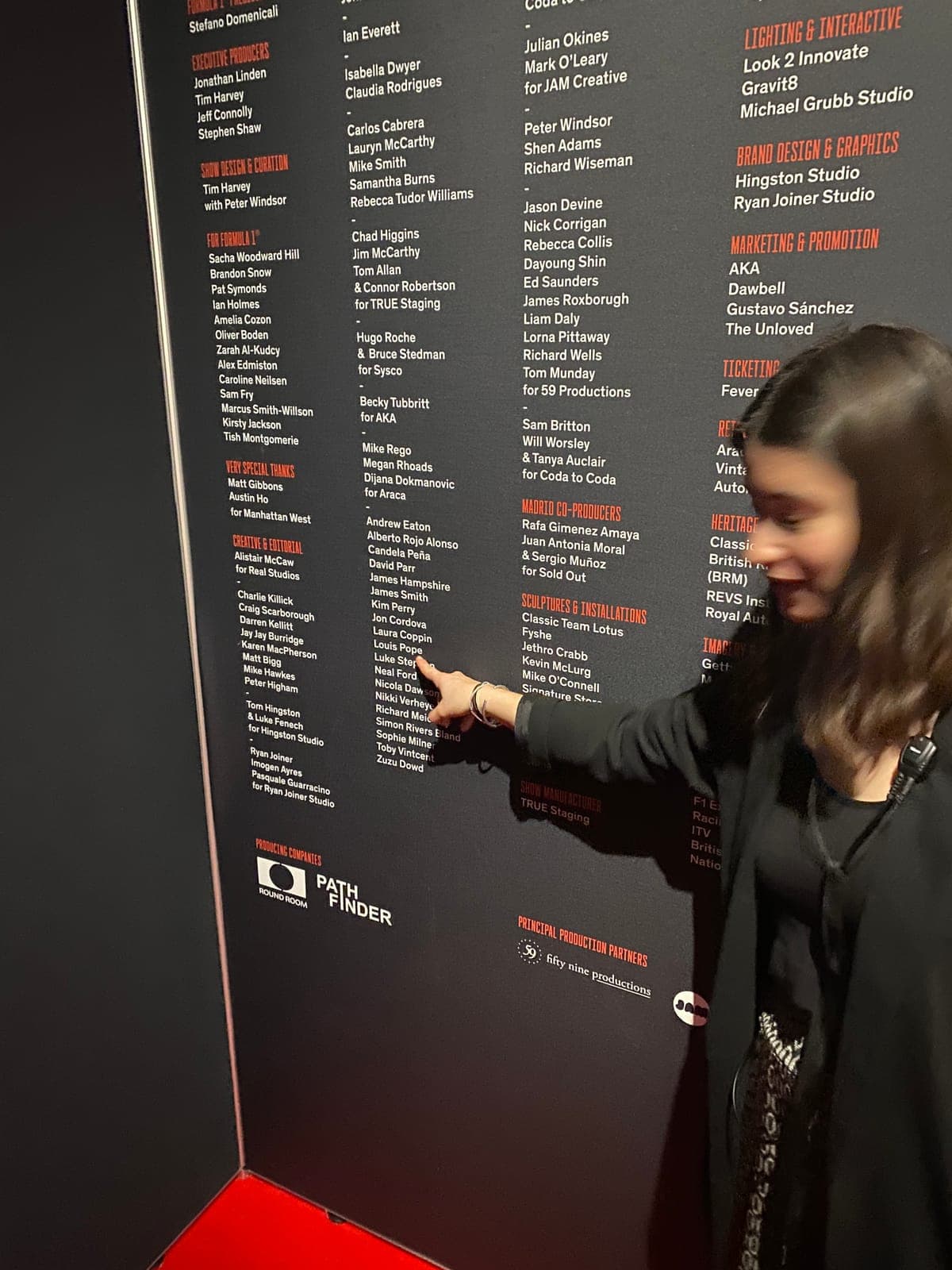 Pointing at Louis Pope on the exhibition credits wall