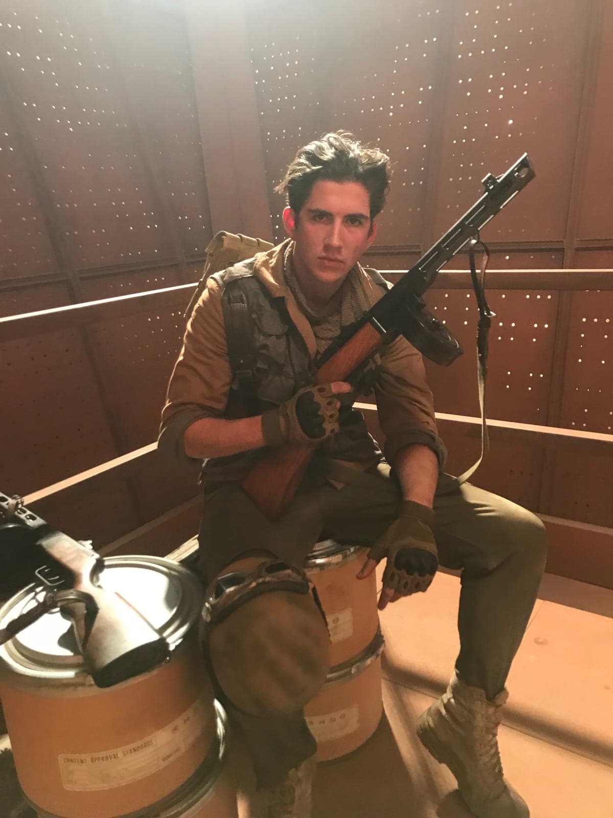 In costume with a prop rifle between takes